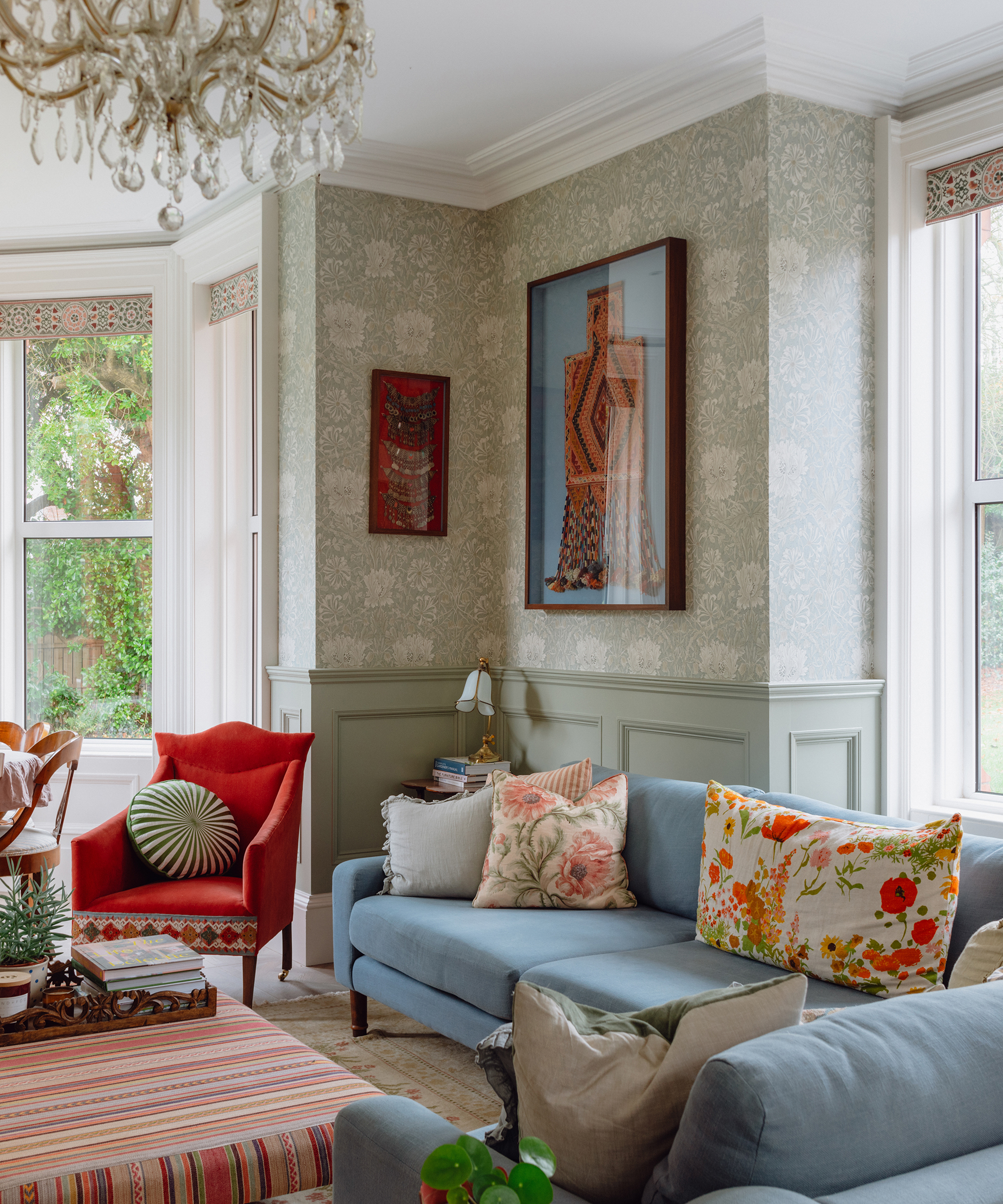 Living room in. Victorian home with patterned wallpaper, wall panelling and bright upholstery and artwork