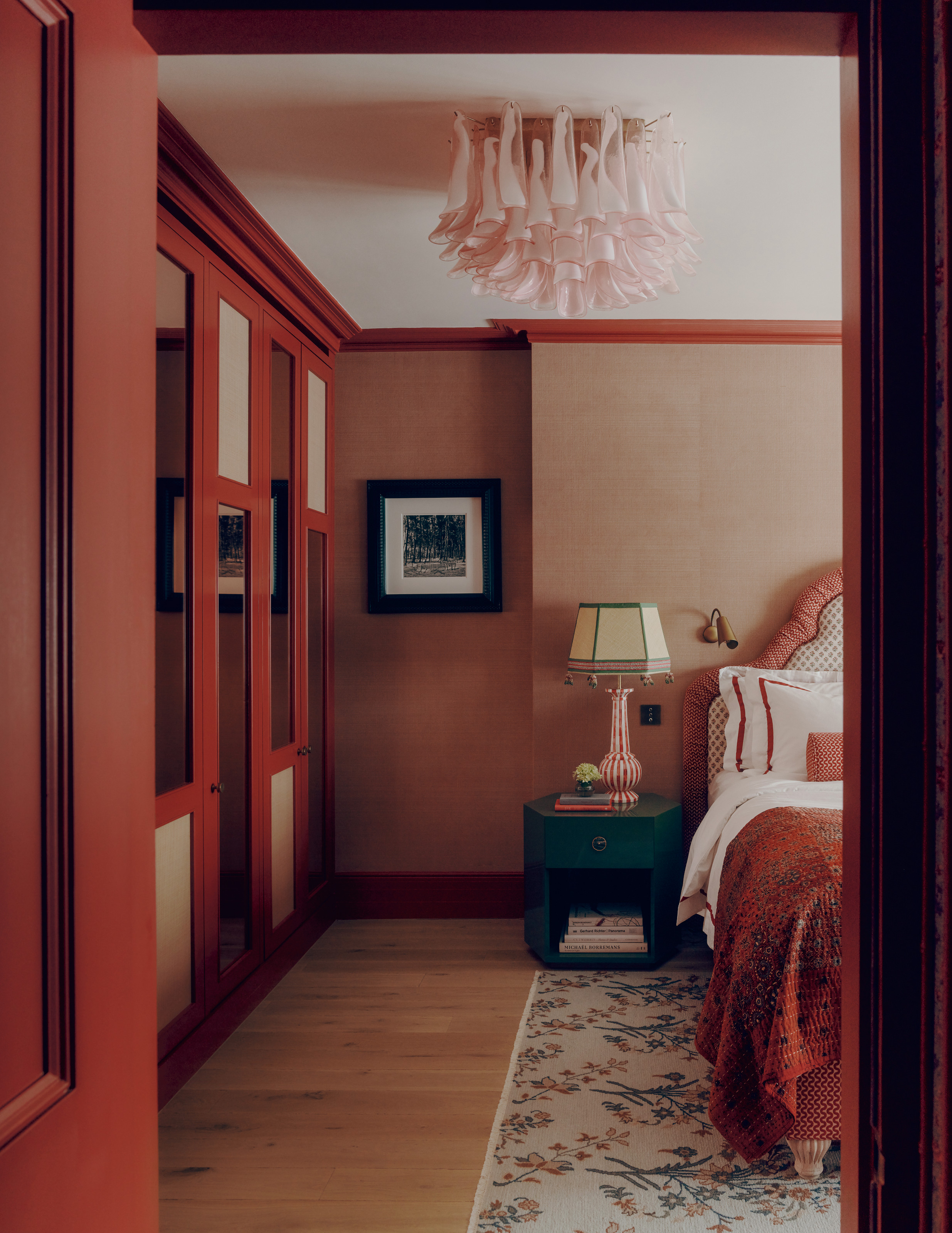 Red living room with build-in wardrobes, upholstered bed and emerald green bedside table