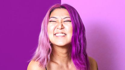 A Korean woman with pink and purple hair grins at the camera, gemini hair