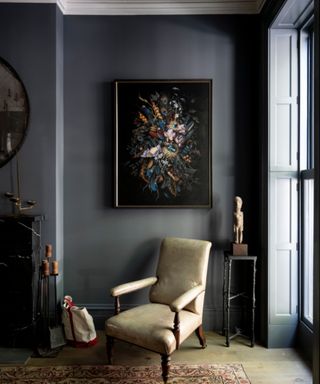 living room with dark gray walls, beige armchair and dark floral artwork on walls