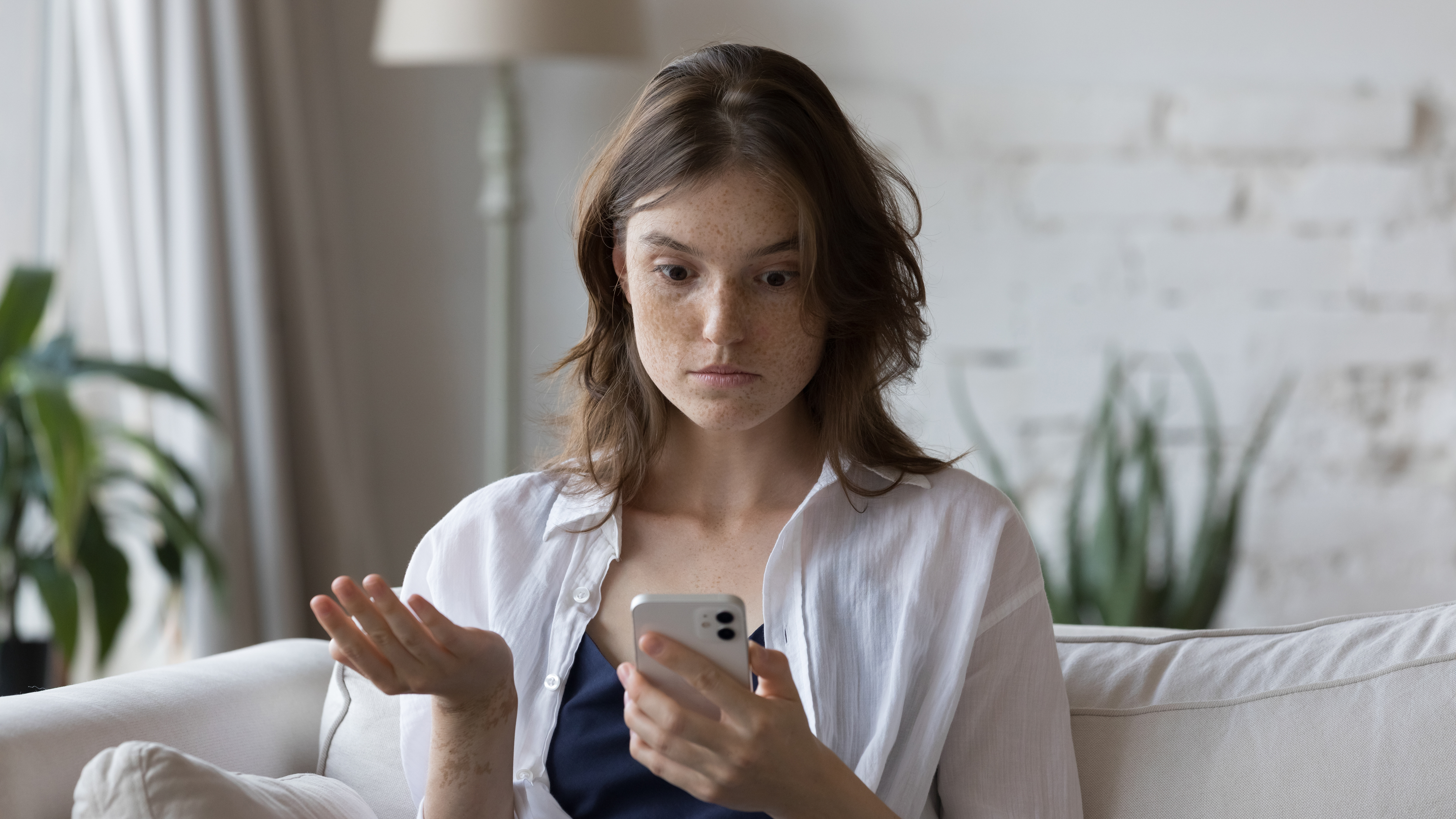 A woman staring at her phone looking confused