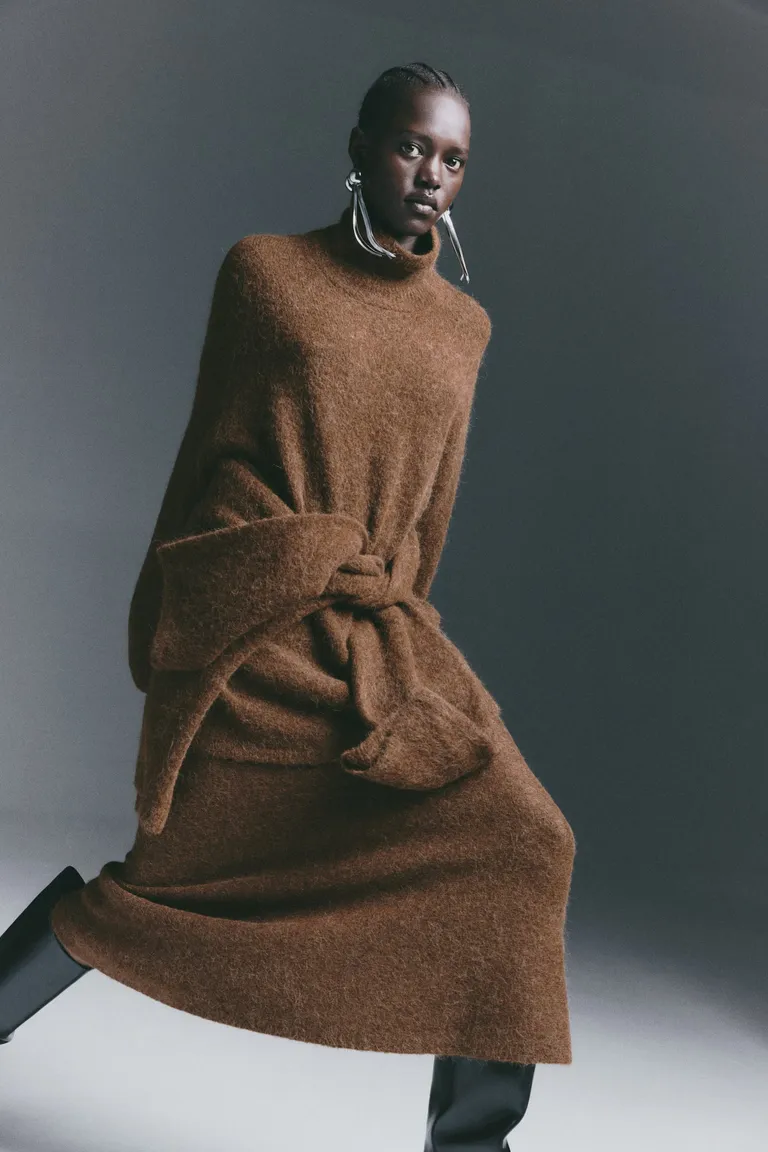 Woman wears brown turtleneck sweater and matching brown skirt