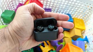 Best cheap wireless earbuds hero image showing the 1More PistonBuds Pro earbuds being held in hand over a ball pit