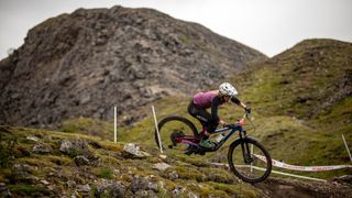 A female rider rails a muddy exposed corner at Ard Rock Enduro 2021