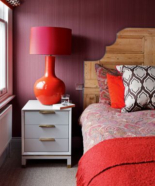 Small bedroom ideas in a red scheme with large lamp and red walls.