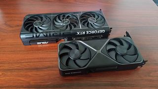 RTX 5070 Founders Edition and Asus Prime OC model lying side by side on woodgrain desk