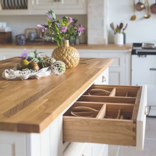 open drawer in country kitchen with cream cabinetry and walls with white aga