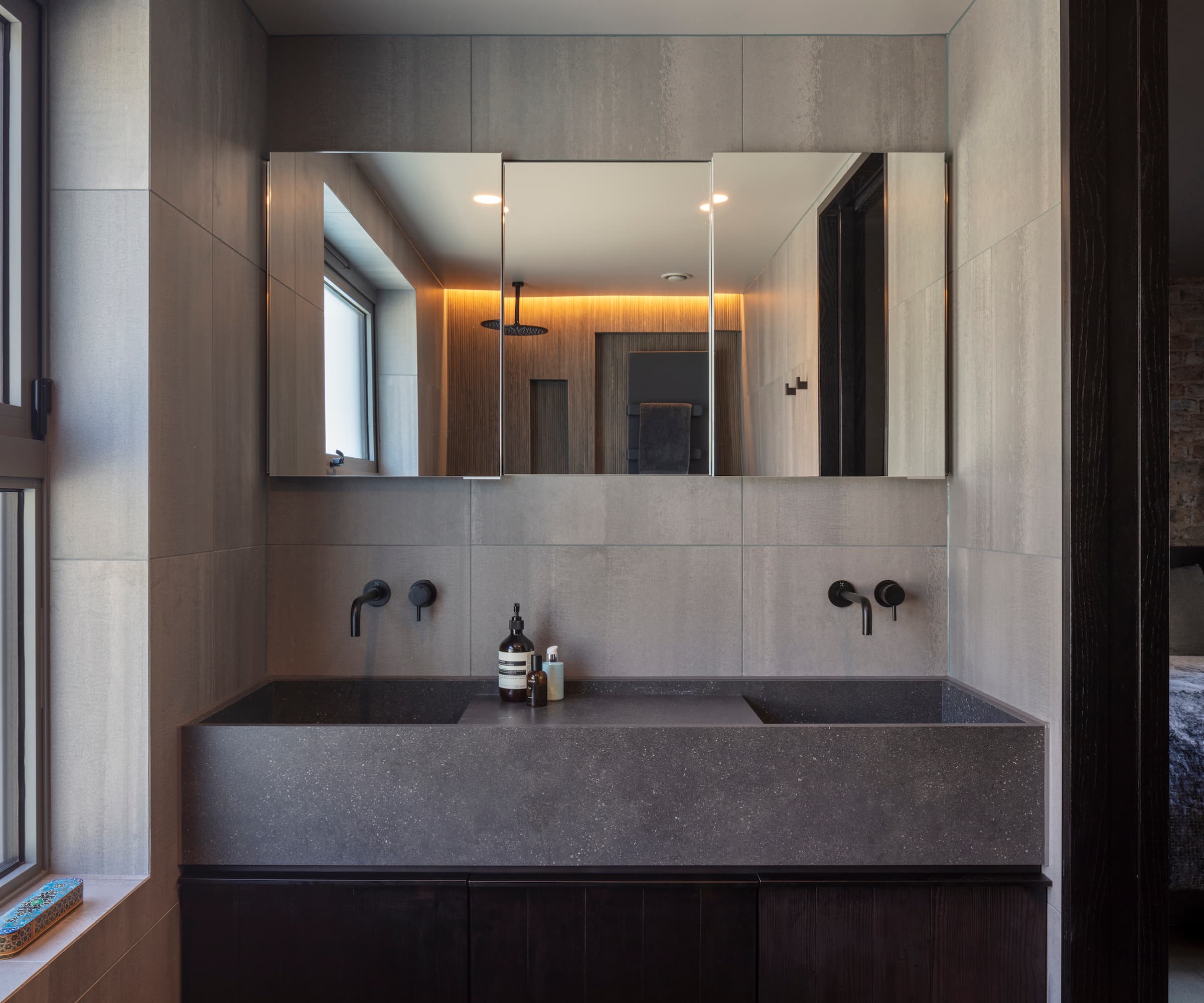 A black bathroom with mirrors and a pair of grey sinks