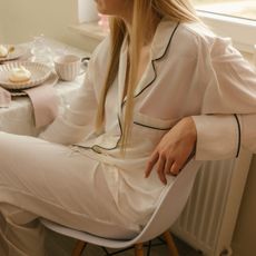 Woman wearing pajamas sitting on chair at dining table at home - stock photo