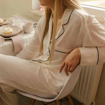 Woman wearing pajamas sitting on chair at dining table at home - stock photo