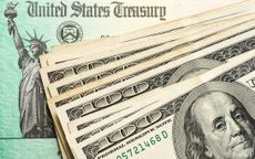 multiple hundred dollar bills on top of a federal tax refund check