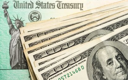 multiple hundred dollar bills on top of a federal tax refund check