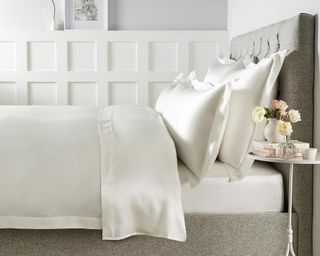 Audley Pure Silk Bed Linen Collection dressed on grey bed frame with white panelled walls behind