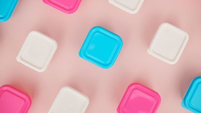 Assorted plastic storage containers on pink background - stock photo