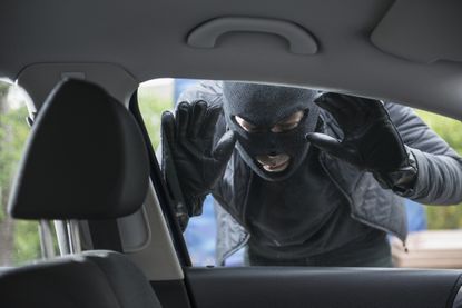 Thief is looking in the window of a car. 