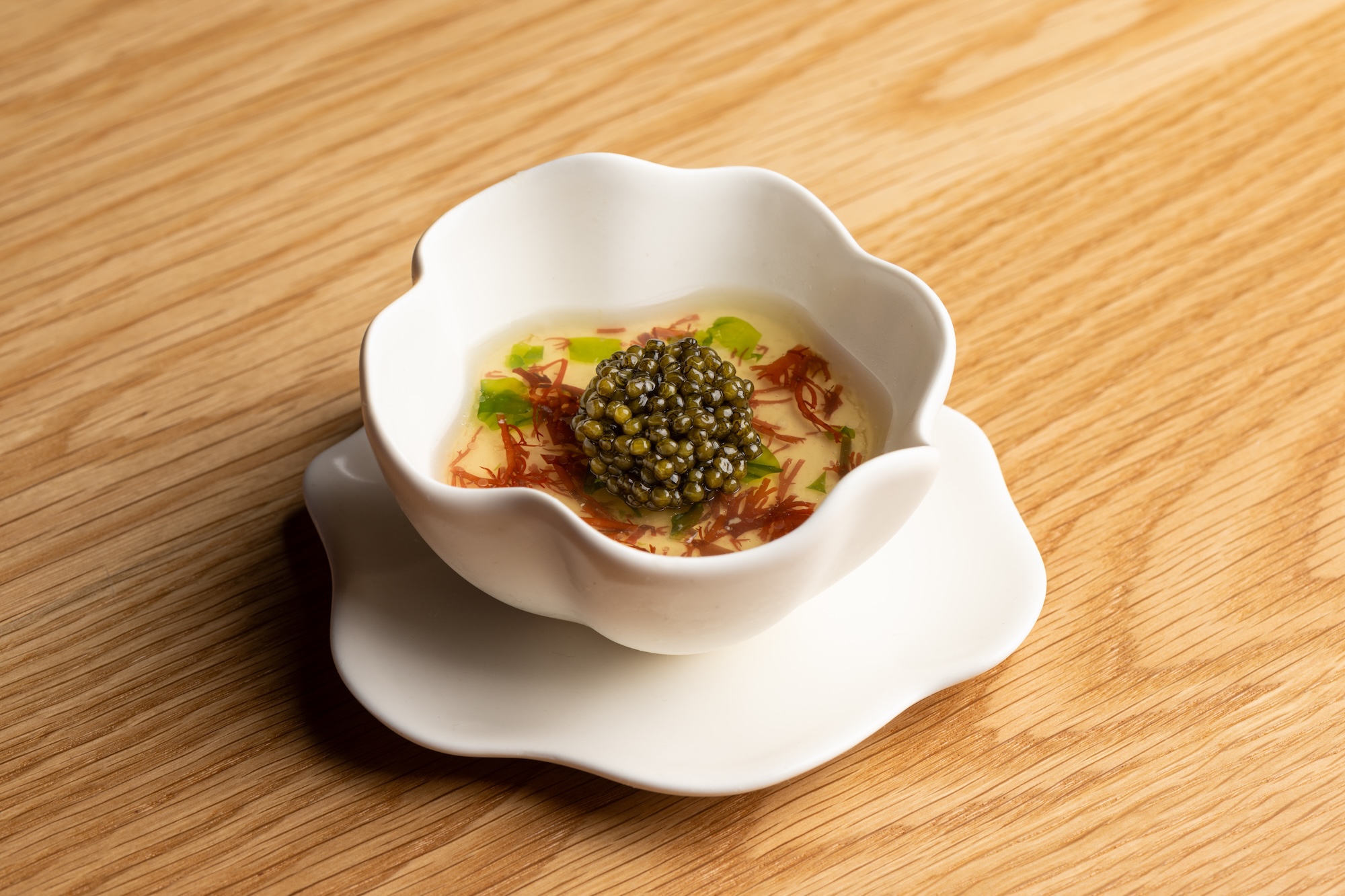 a dish from jacaranda los angeles in a scalloped vessel and a mound of caviar