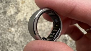Someone holding the Ringconn smart ring against a concrete background.