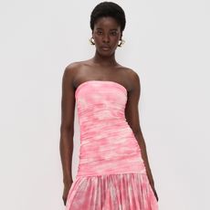 model wears pink and white drop waist dress and heels