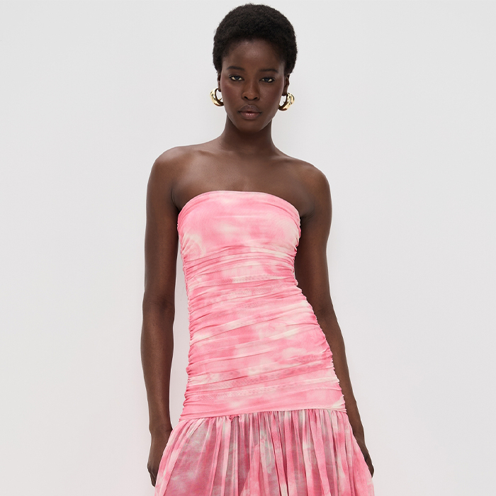 model wears pink and white drop waist dress and heels