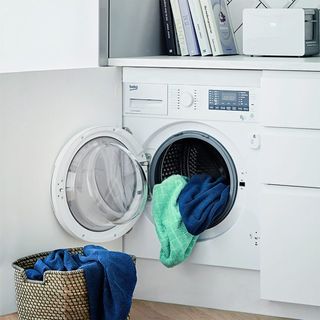 room with white washing machine and basket with clothes