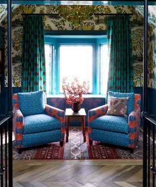 Living room nook with blue and orange chairs and floral wallpaper