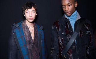 2 male models in dark clothing stood in a studio
