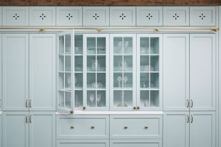 pale blue kitchen cabinets with cutout detail and glazed cupboards with glasses in