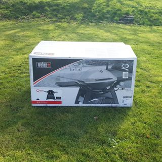 The Weber Q3200 BBQ in a box on a grass lawn