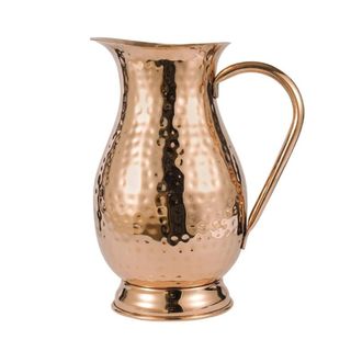 A tall copper hammered jug with a long curved handle