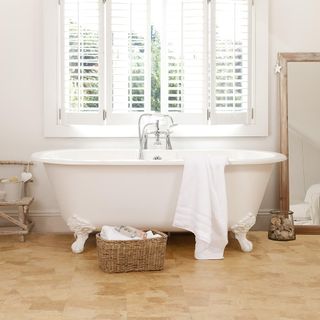 bathroom with white wall and bathtub and amber cork flooring
