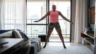 Woman doing jumping jacks in front room