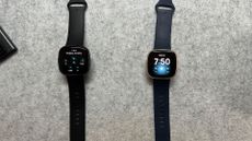 Fitbit Versa 3 and Fitbit Versa 4 laid out on plain grey background