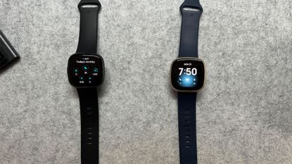 Fitbit Versa 3 and Fitbit Versa 4 laid out on plain grey background