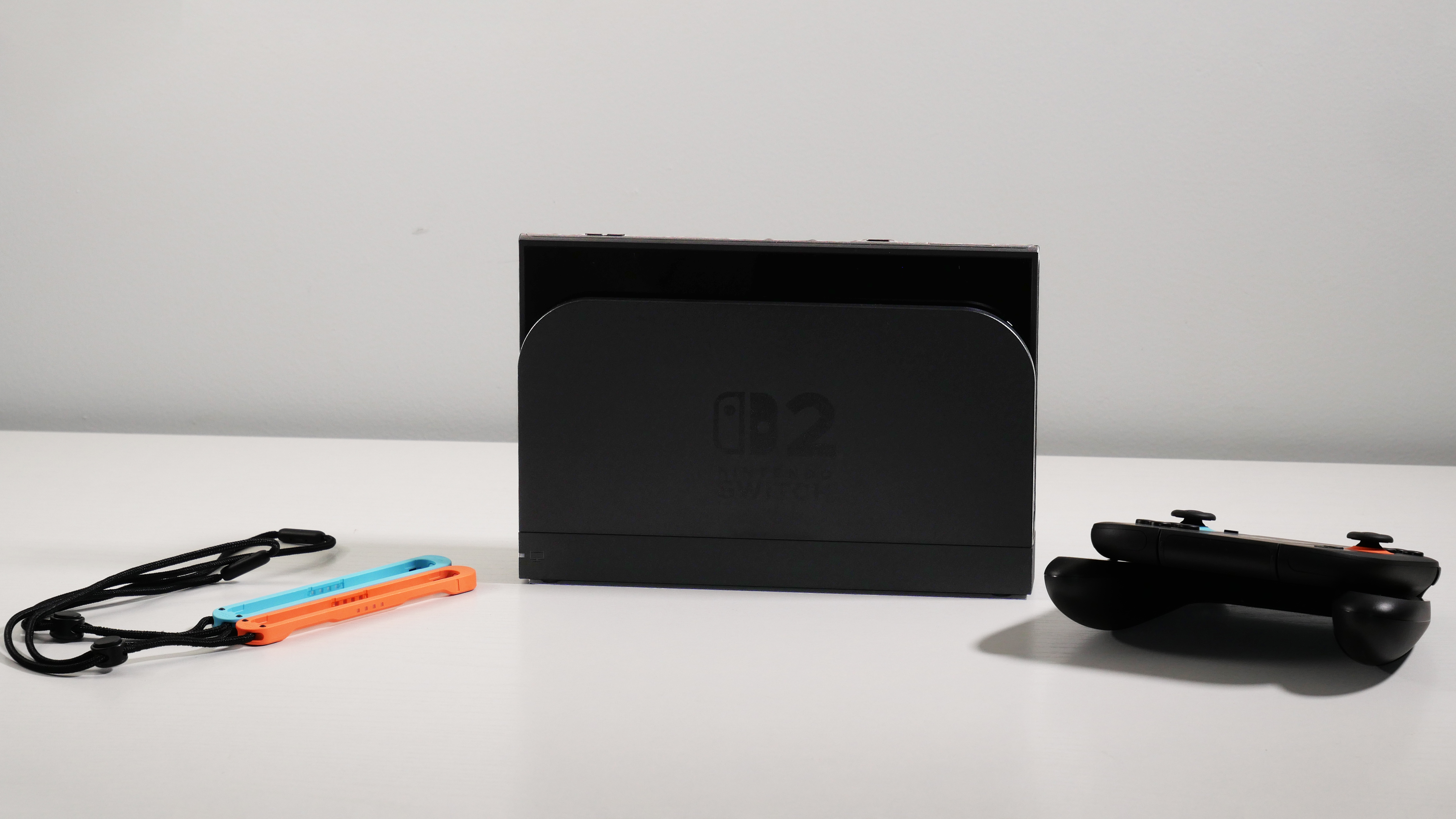 Nintendo Switch 2, Dock, Joy-Con 2 Grip, and Straps displayed on a white desk.