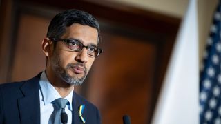 Alphabet and Google CEO Sundar Pichai in a suit with a US flag in the background.