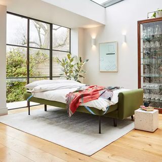 A green Swyft sofa bed in a open plan living room with Crittall doors