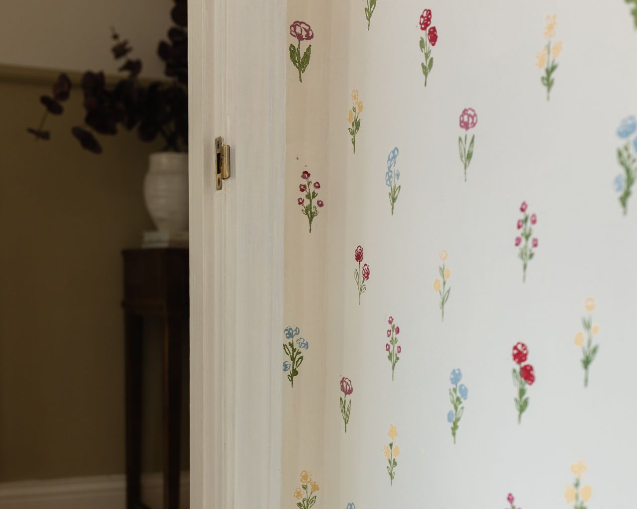 A wall with floral painted stencils and a view through a doorway