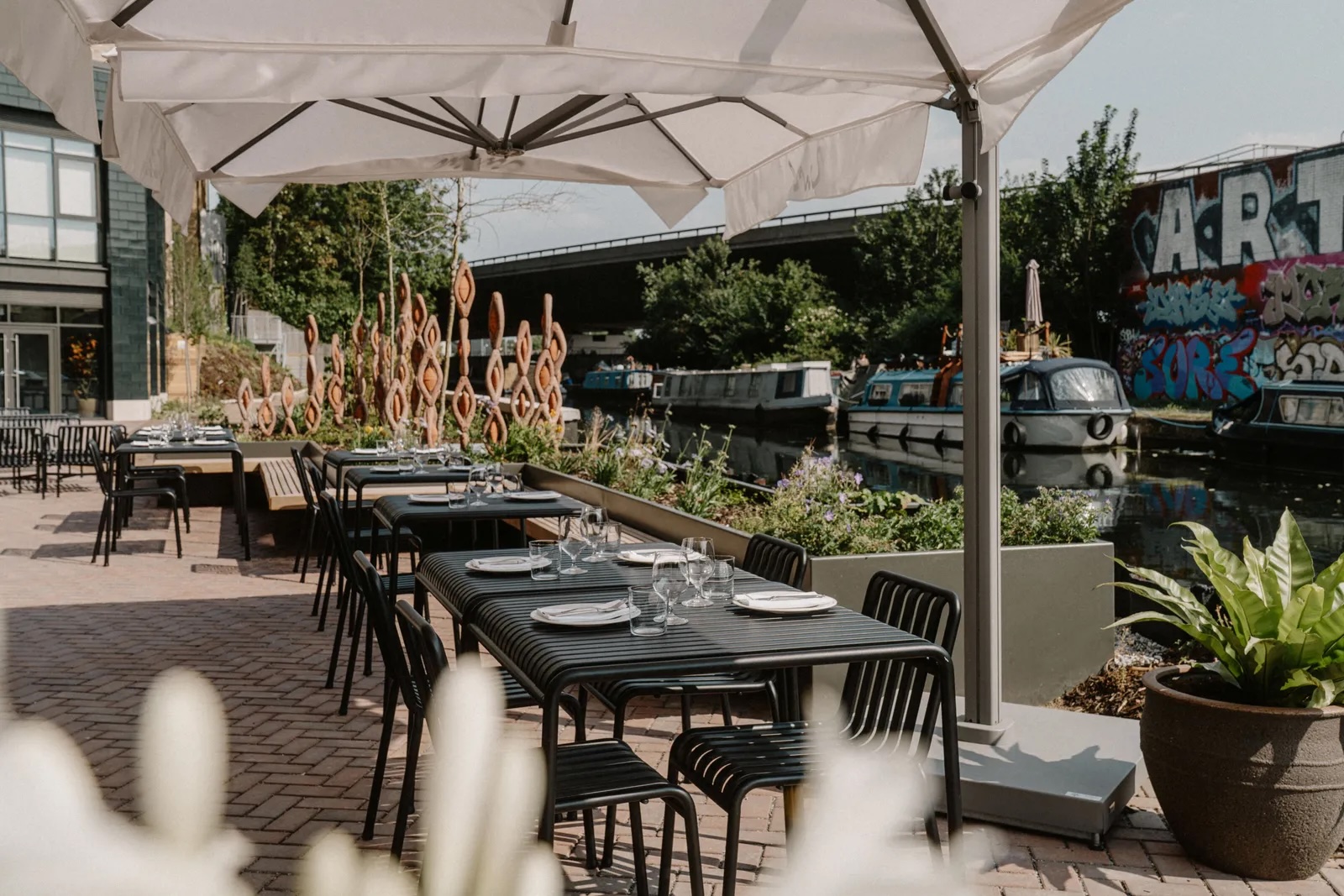 Black metal tables and chairs on a canalside restaurant terrace
