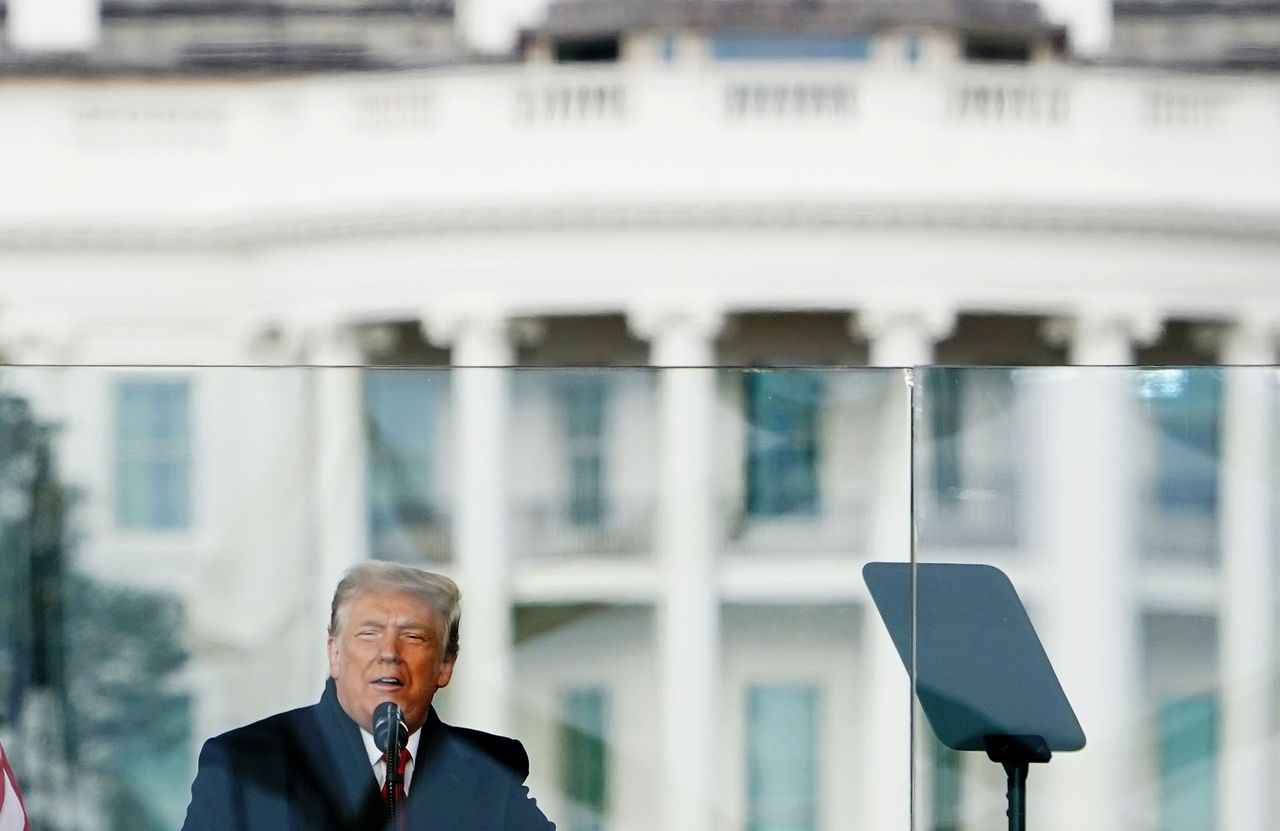 Trump speaks behind bulletproof glass.