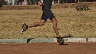 Person running on a track wearing Nike running shoes and compression shorts