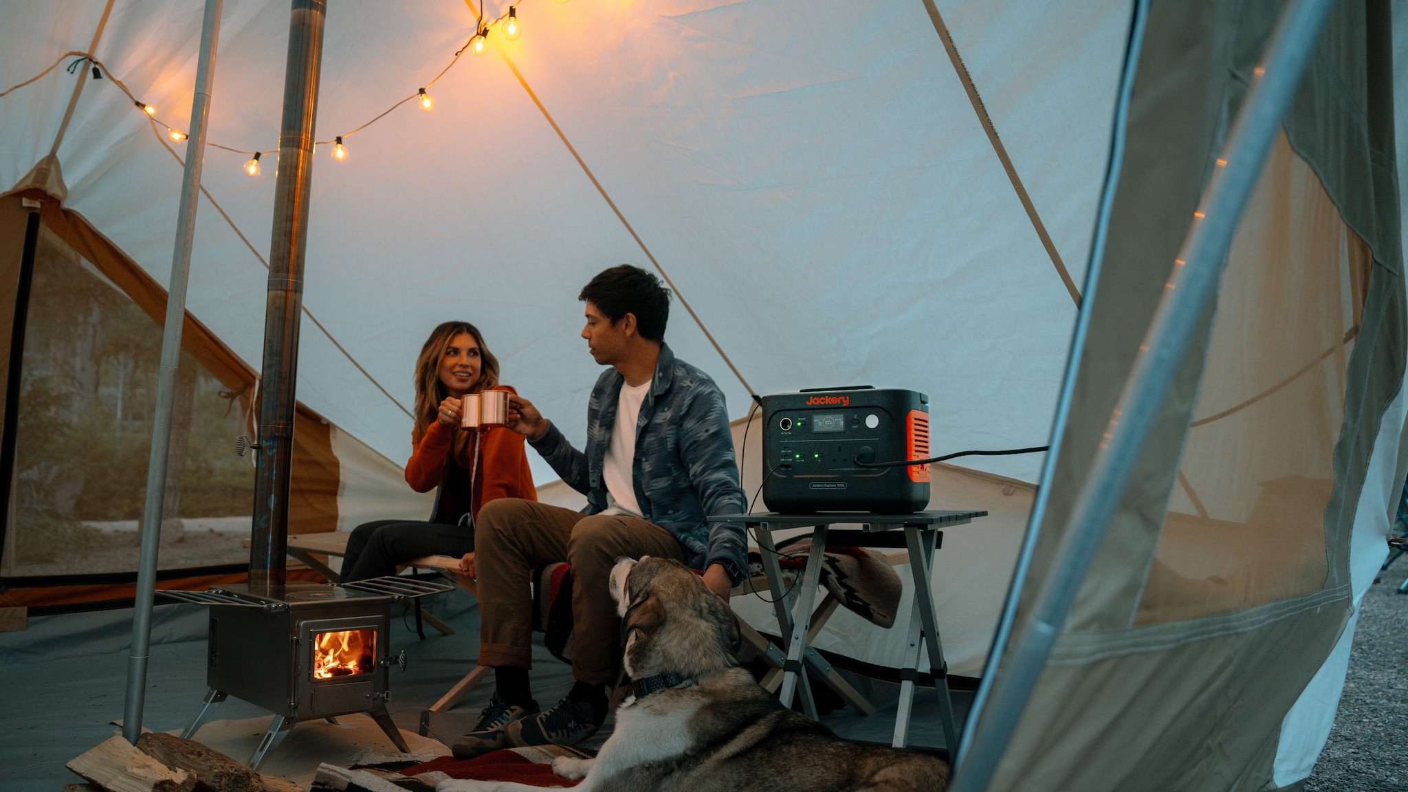 A couple under canvas powering lights with a Jackery portable power station