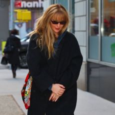 Jennifer Lawrence walks down the street in New York wearing navy felted shoes, cream trousers and a black coat.
