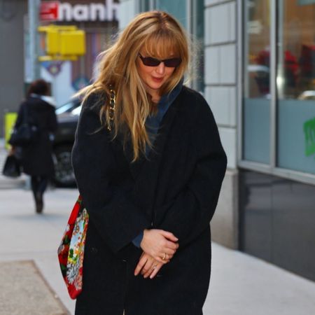 Jennifer Lawrence walks down the street in New York wearing navy felted shoes, cream trousers and a black coat.