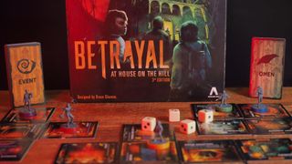 The Betrayal at House on the Hill box, dice, tokens, and board pieces on a wooden table