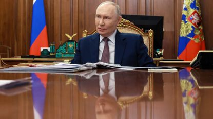 Vladimir Putin sits at a large shiny table