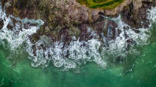 An aerial view of waves crashing up the Cornish coast.