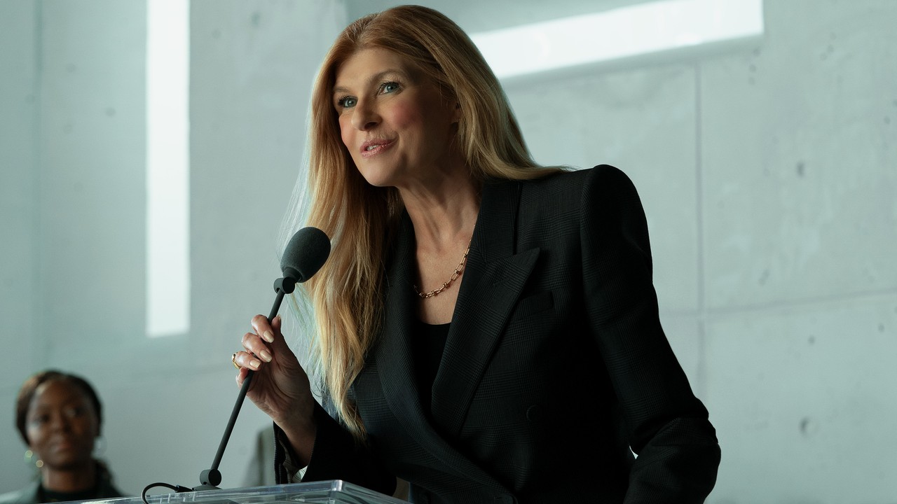 Connie Britton as Elizabeth in Rooster speaking to a crowd with microphone in hand
