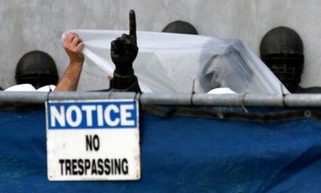 Workers wrap the state of late Penn State football coach Joe Paterno as they prepare to remove it July 22.