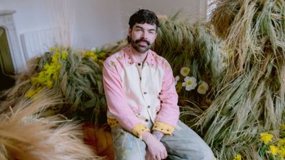Floral designer Mikey Putnam sits among a display of grasses