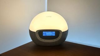 The Lumie Bodyclock Shine 300 with the light on a bedside table.